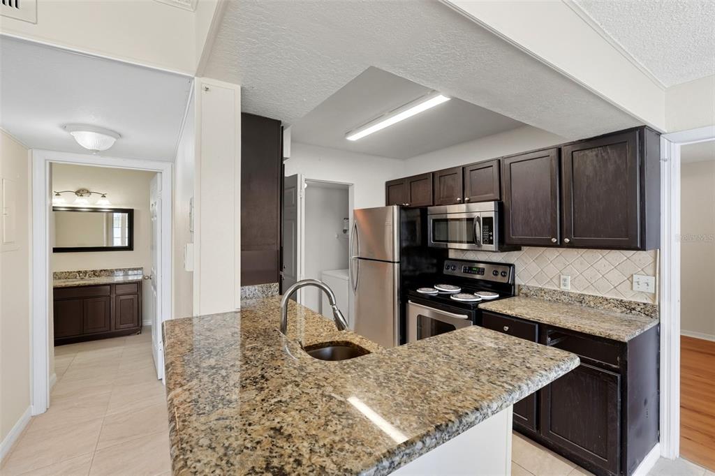 1039 South Hiawassee Road, Unit 2918 Orlando, FL 32835 - Photo 13 of 28 a kitchen with stainless steel appliances kitchen island granite countertop a stove refrigerator and sink