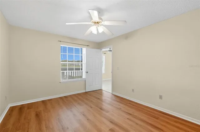 an empty room with wooden floor closet and windows