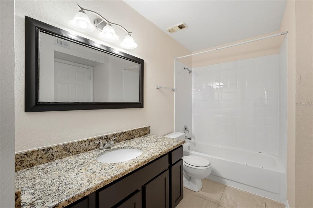 1039 South Hiawassee Road, Unit 2918 Orlando, FL 32835 - Photo 23 of 28 a bathroom with a granite countertop sink a toilet and a mirror