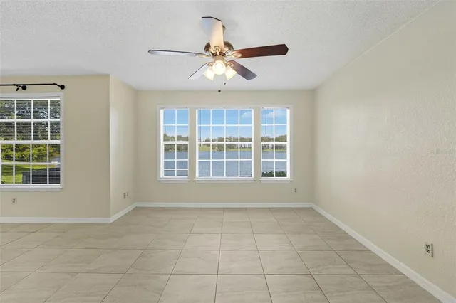 an empty room with chandelier fan and windows