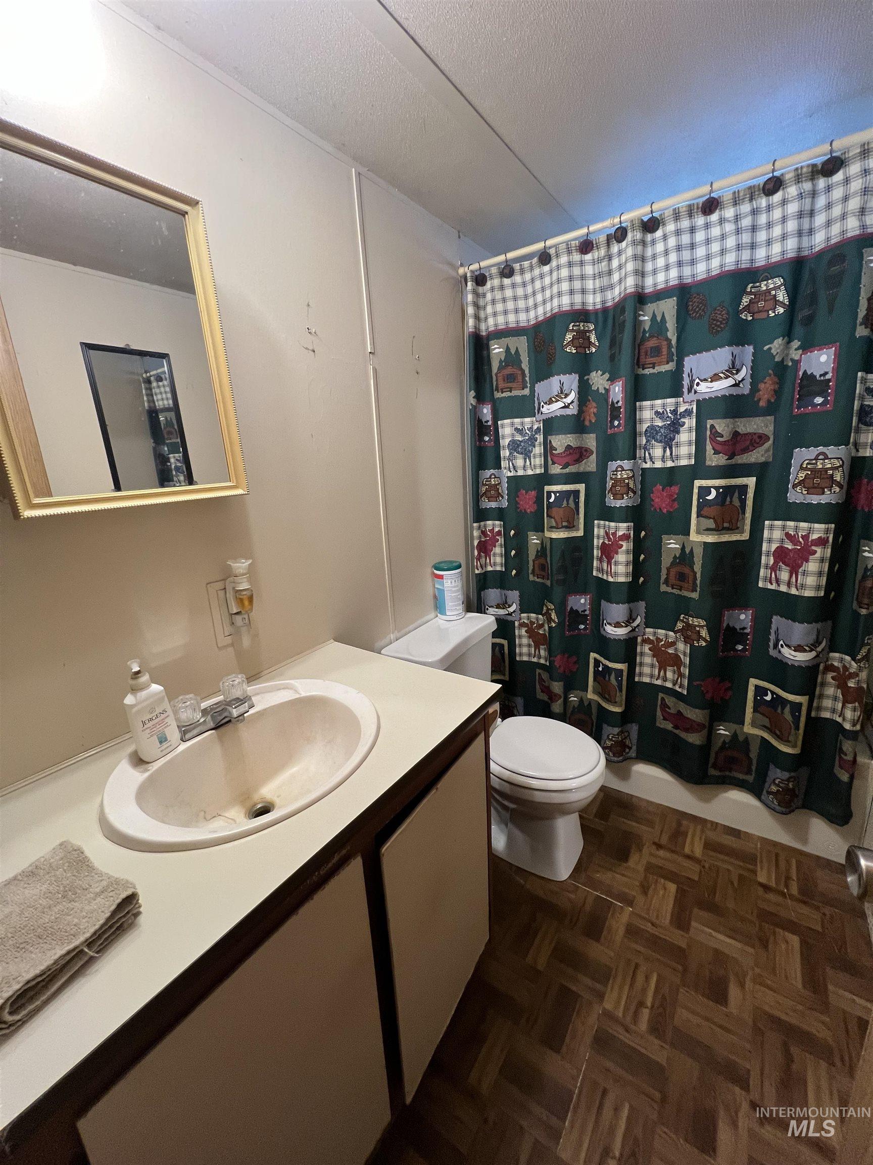 23743 Stephen Lane Parma, ID 83660 - Photo 30 of 34 Bathroom featuring vanity, a textured ceiling, parquet flooring, and shower / bathtub combination with curtain