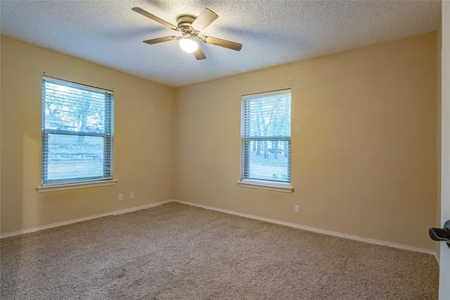 an empty room with windows and fan