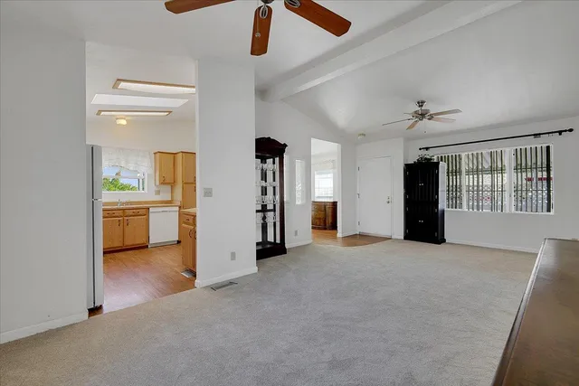 an empty room with chandelier fan and windows