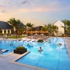 17439 Chester Valley Trail Hockley, TX 77447 - Photo 20 of 22 This photo showcases a modern community pool area with lounge chairs, umbrellas, and surrounding greenery, perfect for relaxation and socializing.