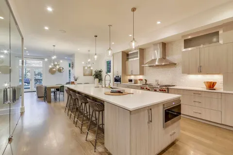 a large white kitchen with a stove a sink a refrigerator and a dining table with wooden floor