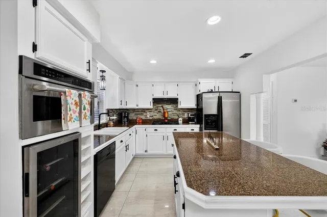 a large kitchen with stainless steel appliances granite countertop a sink a stove and a refrigerator