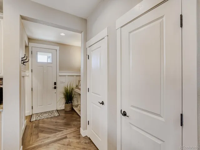 a kitchen with kitchen island granite countertop a refrigerator a stove a sink dishwasher a oven with white cabinets and wooden floor