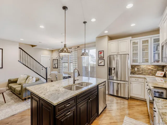 a view of a kitchen with kitchen island stainless steel appliances a sink center island and living room view