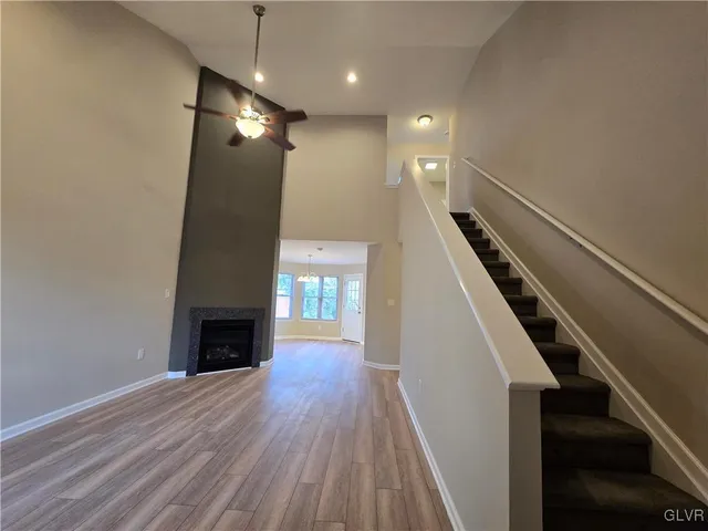 a view of an empty room with wooden floor fireplace and a window