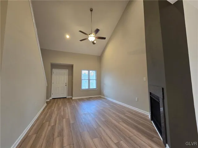 a view of an empty room with a window and wooden floor