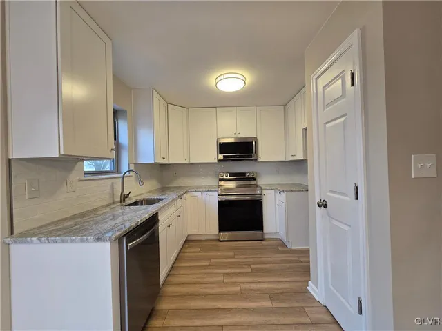 a kitchen with stainless steel appliances granite countertop a stove a sink and a refrigerator