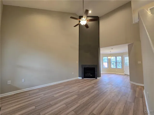 an empty room with wooden floor fireplace and windows