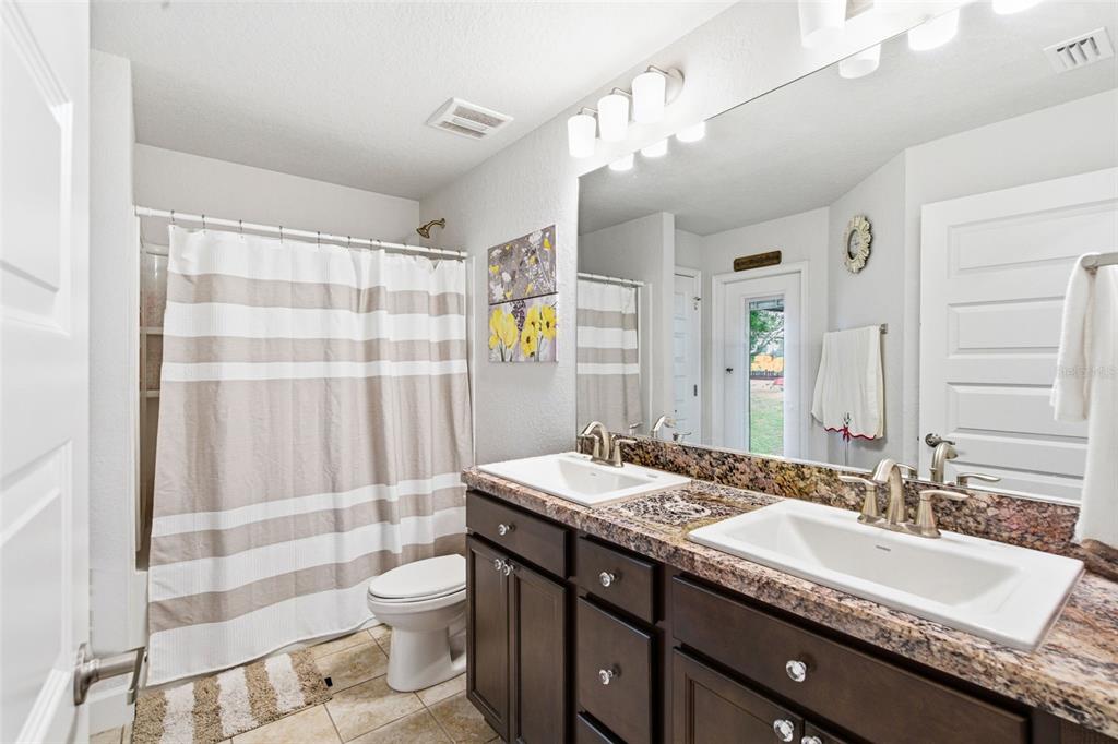 12181 Topaz Street Spring Hill, FL 34608 - Photo 30 of 71 a bathroom with a granite countertop double vanity sink toilet and shower