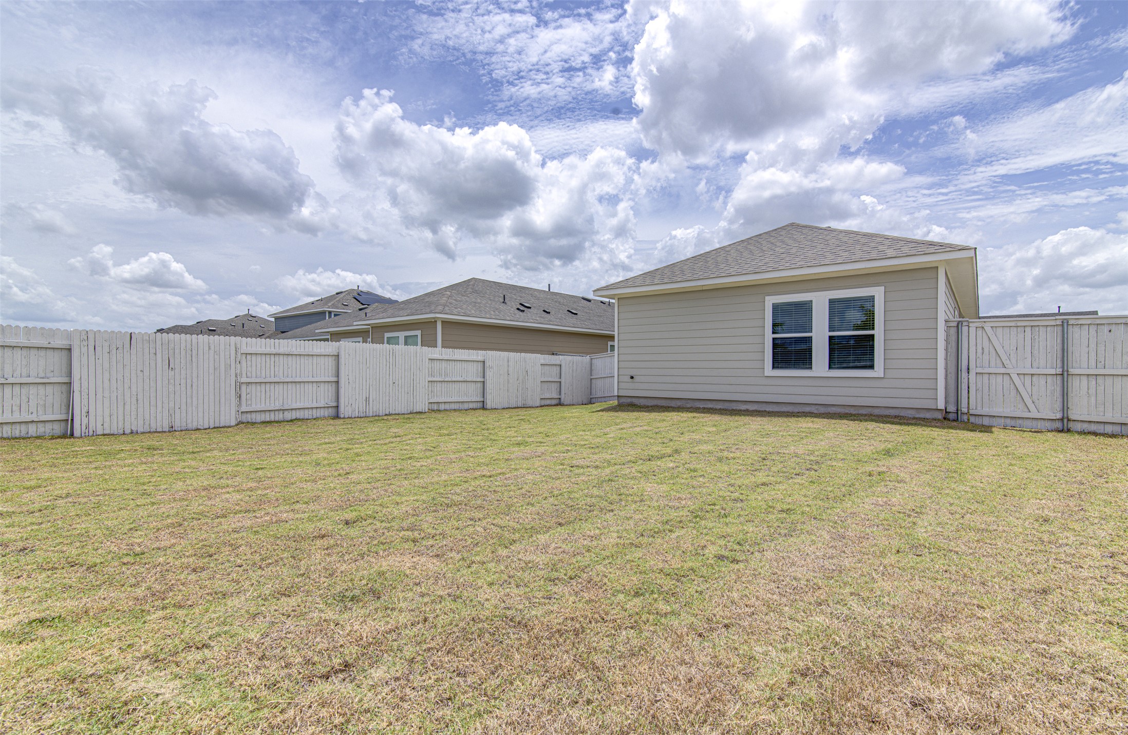 156 Tillage Road Elgin, TX 78621 - Photo 23 of 25 A spacious backyard awaits, fully fenced for privacy and outdoor enjoyment.