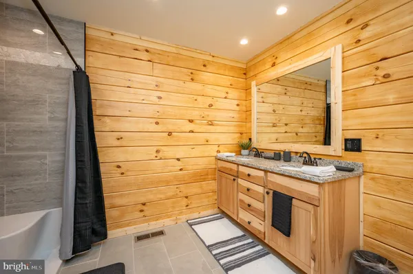 a bathroom with a granite countertop sink and a bathtub