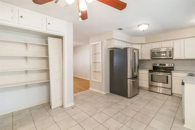 a kitchen with a refrigerator and white cabinets