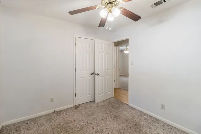 an empty room with closet and a chandelier fan