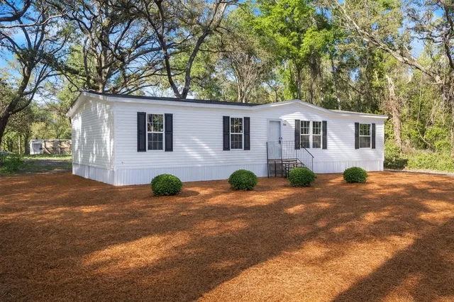 a view of a house with backyard and trees