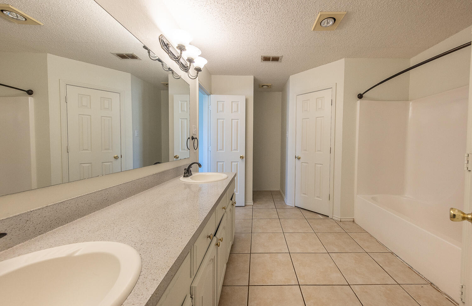 6109 13th Street Lubbock, TX 79416 - Photo 13 of 24 a spacious bathroom with a granite countertop sink a mirror and a bathtub