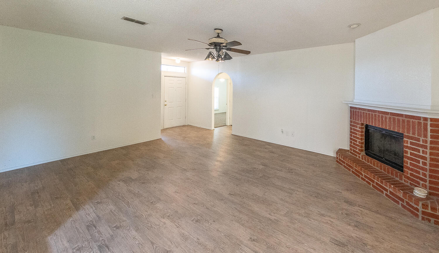 6109 13th Street Lubbock, TX 79416 - Photo 4 of 24 an empty room with a fireplace and a chandelier fan