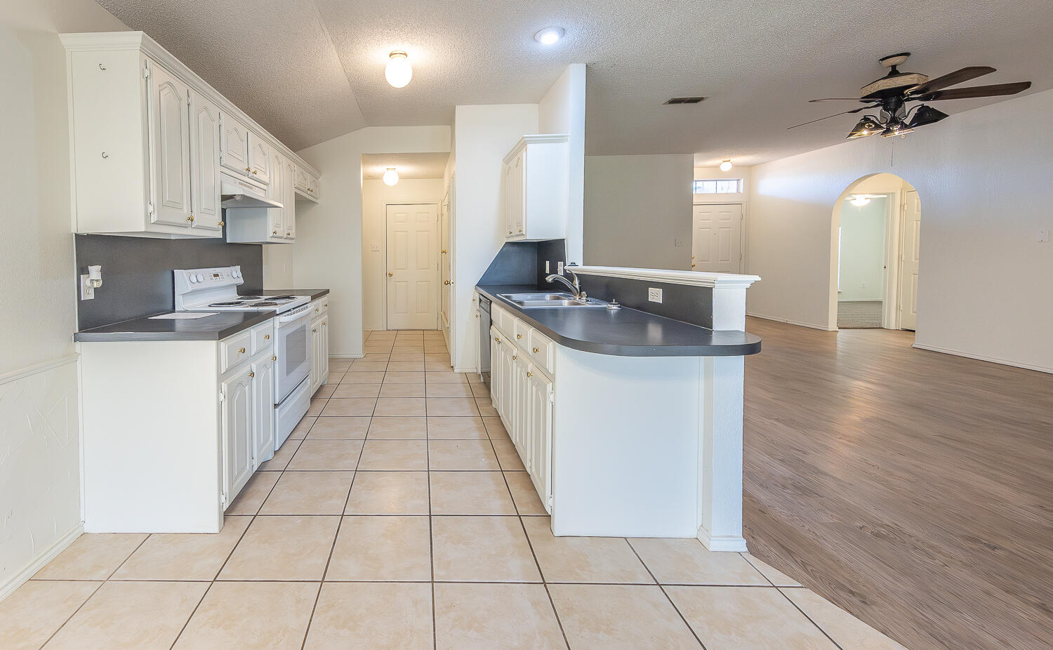 6109 13th Street Lubbock, TX 79416 - Photo 8 of 24 a large white kitchen with a stove a sink a refrigerator a microwave and cabinets
