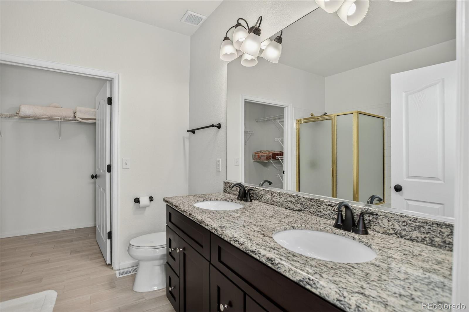203 Remuda Lane, Unit 203 Lafayette, CO 80026 - Photo 22 of 35 a bathroom with a granite countertop double vanity sink a mirror and a shower