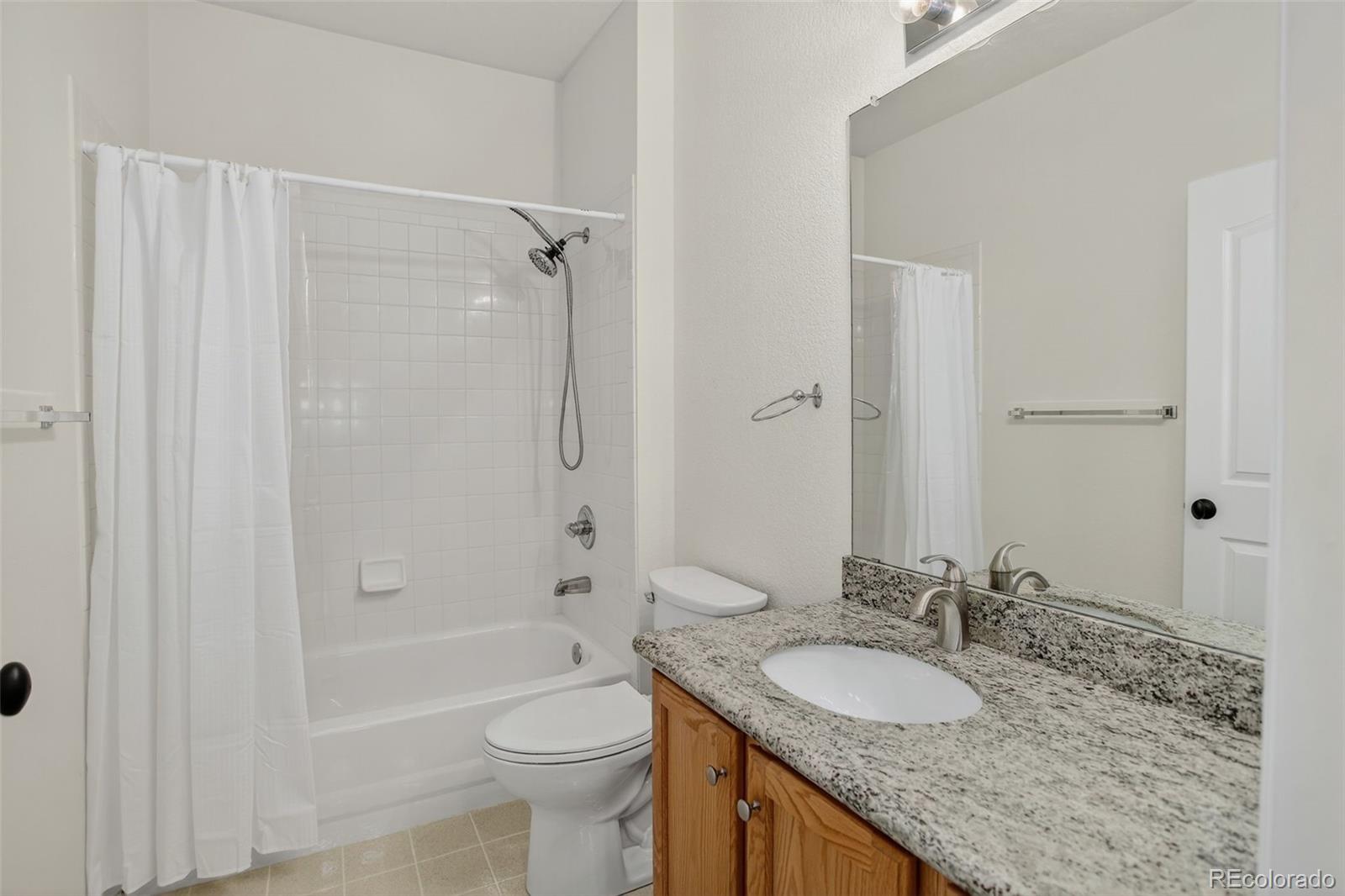 203 Remuda Lane, Unit 203 Lafayette, CO 80026 - Photo 26 of 35 a bathroom with a granite countertop sink toilet and shower