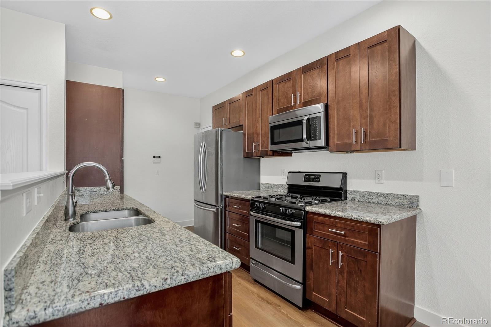 203 Remuda Lane, Unit 203 Lafayette, CO 80026 - Photo 10 of 35 a kitchen with granite countertop wooden cabinets stainless steel appliances and a counter space
