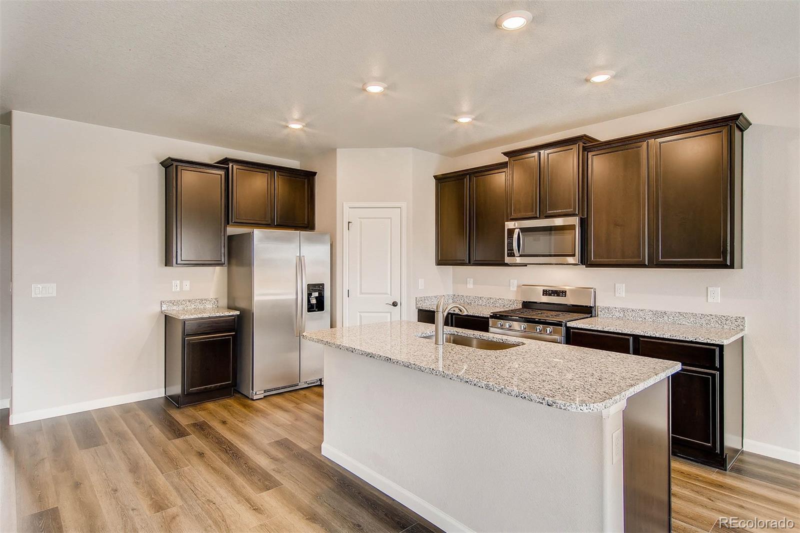 2299 Murray Street Mead, CO 80504 - Photo 15 of 17 a kitchen with stainless steel appliances granite countertop a stove a sink and a refrigerator with wooden floor