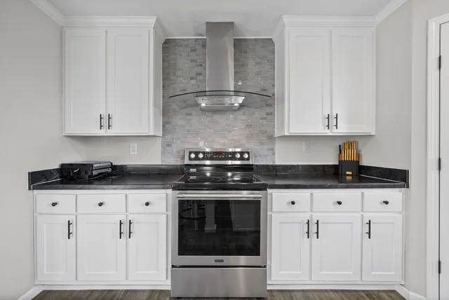 a kitchen with granite countertop white cabinets and stainless steel appliances