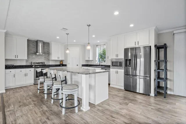 a kitchen with white cabinets stainless steel appliances and wooden floor