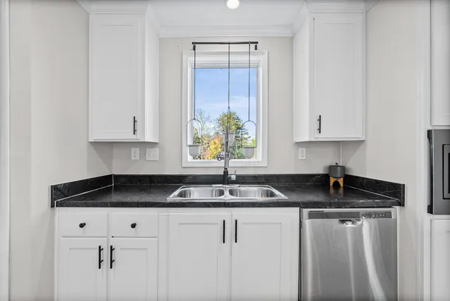 a kitchen with granite countertop white cabinets sink and window