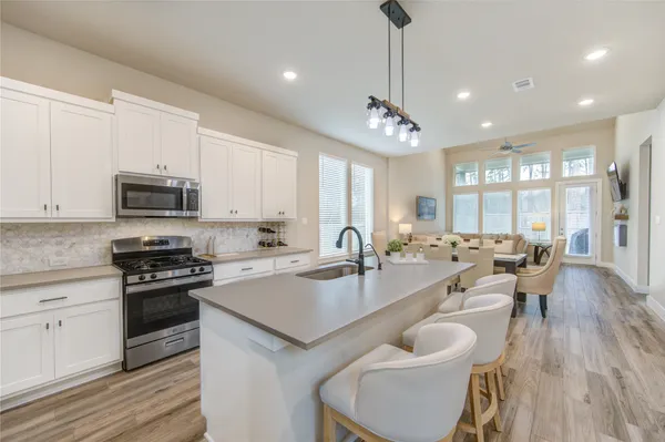 a large kitchen with sink a refrigerator and chairs