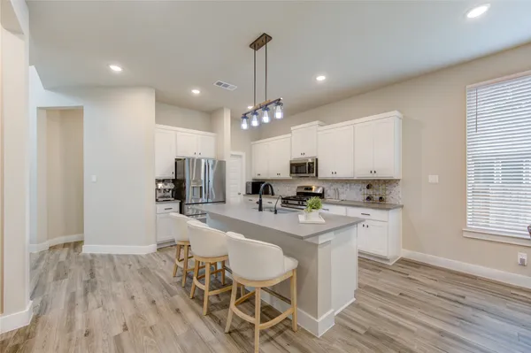 a kitchen with kitchen island granite countertop a sink cabinets and wooden floor