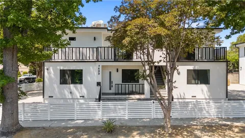 a view of a house with a small yard and large tree