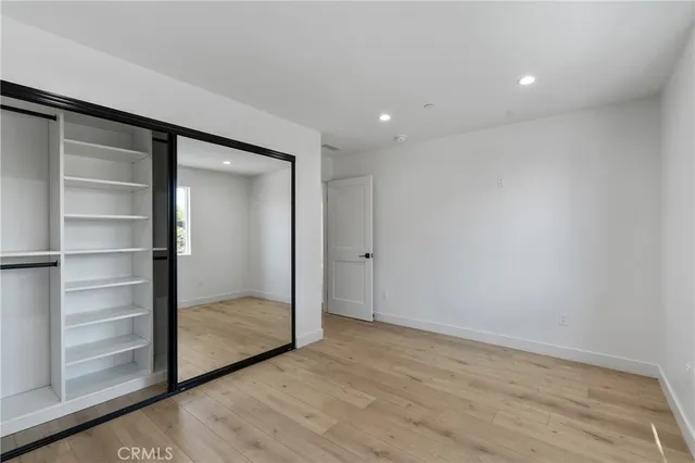 an empty room with wooden floor and a ceiling fan