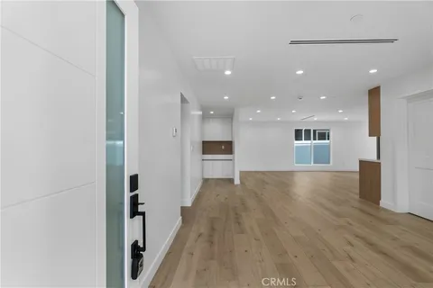 a view of a big room with wooden floor and a kitchen