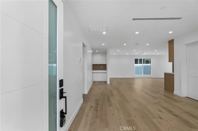 a view of a big room with wooden floor and a kitchen