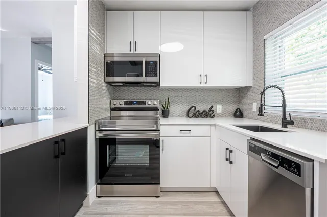 a kitchen with stainless steel appliances granite countertop a sink dishwasher a stove and a microwave oven with wooden floor