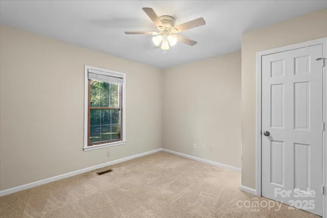 an empty room with a chandelier fan and closet