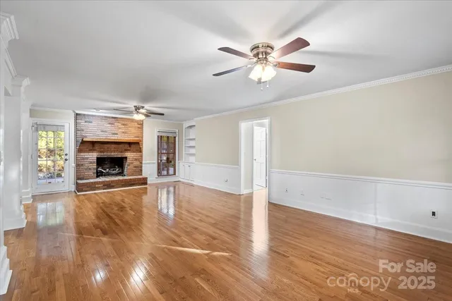 a view of an empty room with window and wooden floor