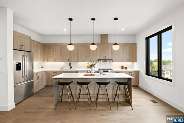 a kitchen with stainless steel appliances granite countertop a sink a stove a refrigerator and island with wooden floor