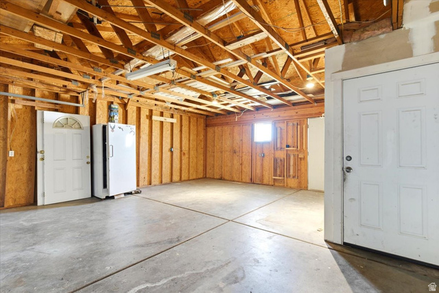 1613 Sunset Road Lake Point, UT 84074 - Photo 27 of 33 Spacious utility room featuring a concrete floor, exposed wooden ceiling joists, wood-paneled walls, and two white panel doors