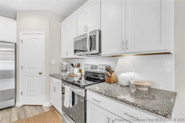 a kitchen with stainless steel appliances granite countertop a stove a sink and a white cabinets