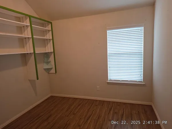 a view of an empty room with a window and wooden floor