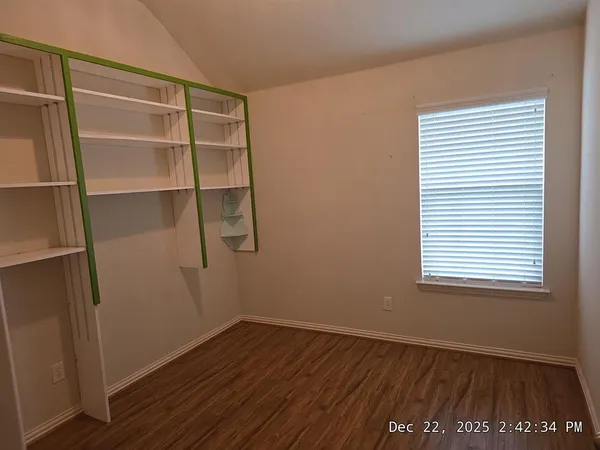 a view of an empty room with a window and wooden floor