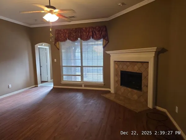 a view of an empty room with wooden floor fireplace and a window