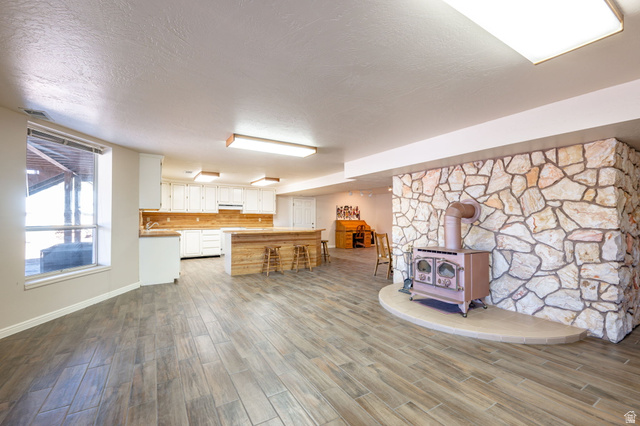 6 South N Frk Road Orderville, UT 84758 - Photo 11 of 68 Kitchen with a wood stove, light countertops, wood finish floors, white cabinets, and a textured ceiling