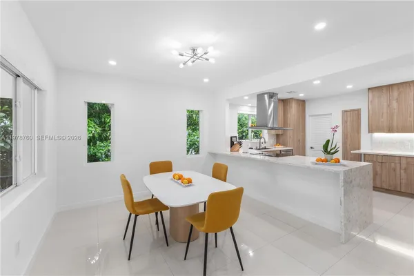 a dining room with a table chairs and a dining table with kitchen view