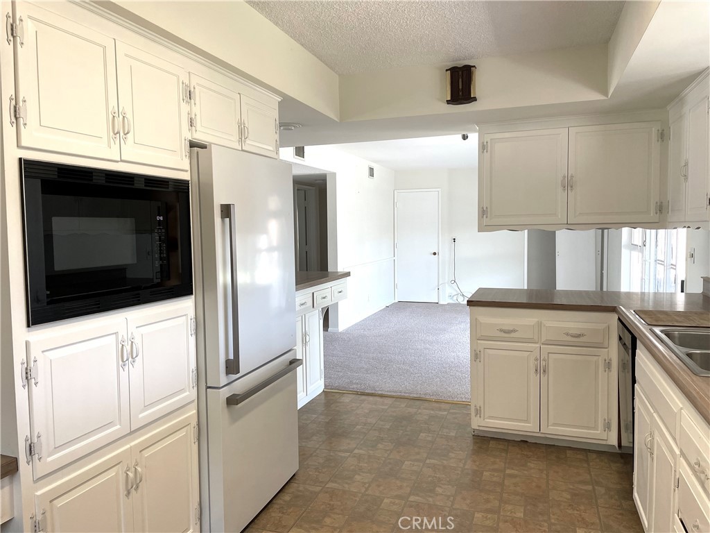 3001 Coleridge Drive Rossmoor, CA 90720 - Photo 4 of 25 a kitchen with granite countertop white cabinets and refrigerator